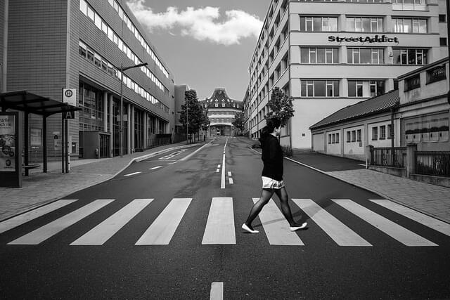 Une photographie en noir et blanc d'une personne qui traverse à un passage piéton.